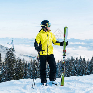 穿着戴滑雪棍头盔的快乐滑雪机站在雪图片