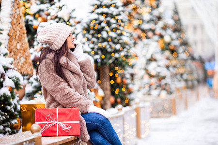 圣诞树附近的漂亮女人在雪地户外的雪屋外图片