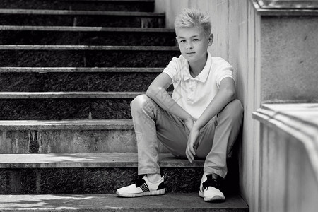 英俊的金发美女11岁男孩青少年坐在户外的楼梯上图片