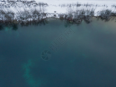 雪的空中景象覆盖湖泊上着陆阶段冬季树木在寒冷清晨图片