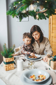 年轻快乐的母亲及其孩子在圣诞节日吃健康早餐图片