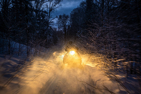 晚上的雪地摩托穿过冬季森林大灯穿过冬季森林的夜路雪背景图片