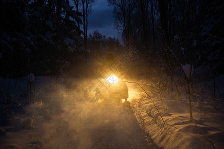 晚上的摩托穿过冬季森林大灯穿过冬季森林的夜路雪图片