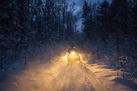 晚上的雪地摩托穿过冬季森林大灯穿过冬季森林的夜路雪图片