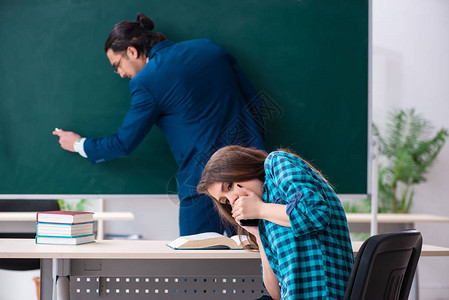 年轻英俊的教师和教室中的女学图片