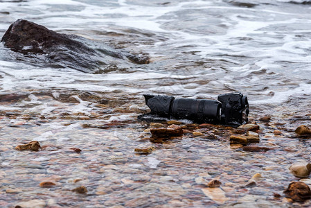 带长焦镜头的单反相机在石滩旅行和测试时被水海浪弄湿图片