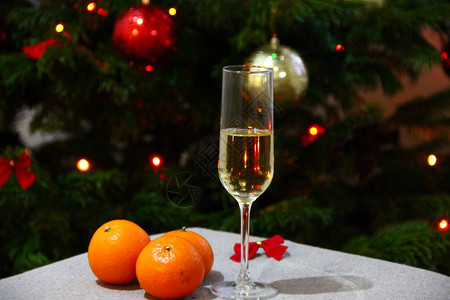 香槟杯和橘子在圣诞树闪亮的灯光旁边图片