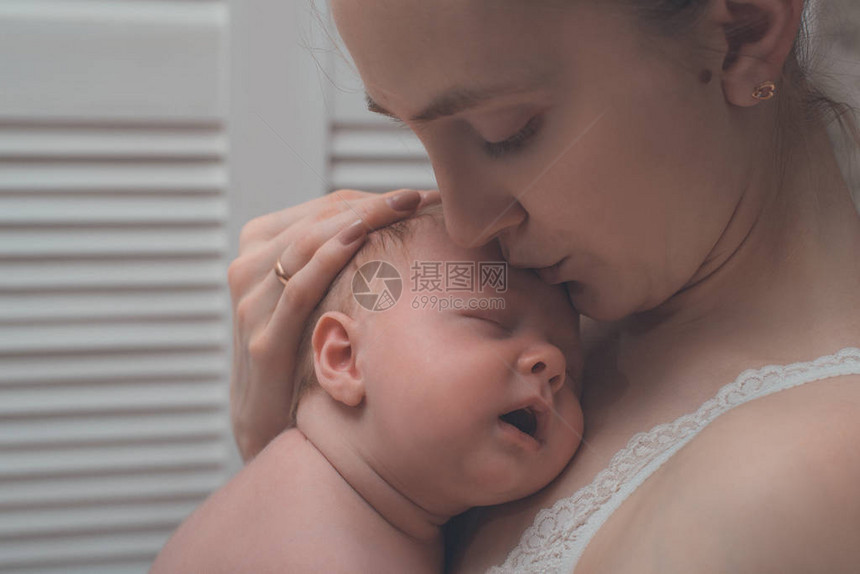母亲怀着金发碧眼的睡婴儿在她的怀里一图片