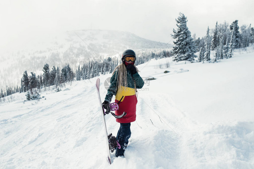 与滑雪板的女滑雪板在雪坡上的山图片