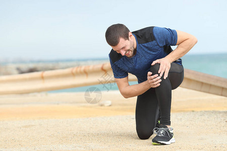 痛苦的跑者抱怨在海滩上运动图片