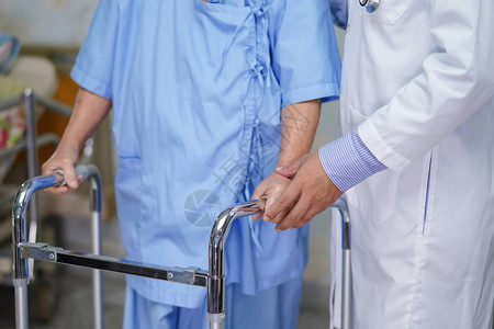 医生护理帮助和支持老年或老年妇人患者在医院病房与步行者同行图片