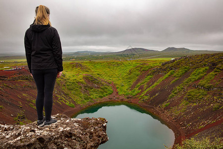 金发女探险家对着天看池塘看着凯里德火山湖全程的远足者站在岩石上她图片