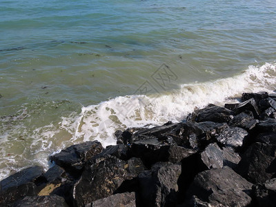 海浪冲洗法国诺曼底阿罗曼切海岸D日海滩的黑岩阳光明日图片