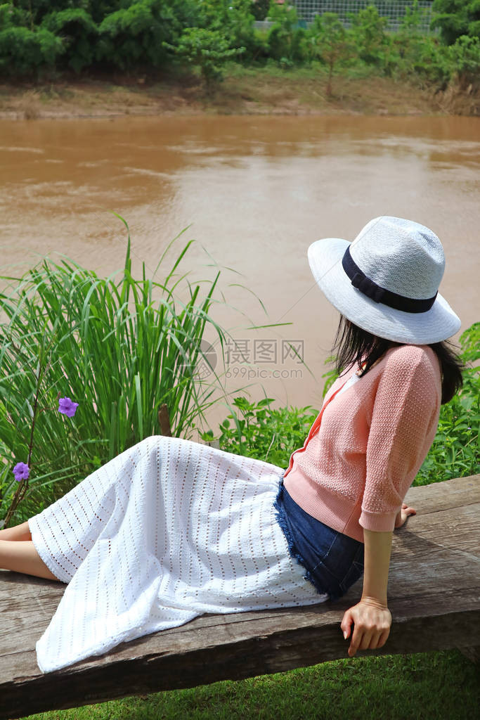 泰国楠府河边长椅上晒太阳的女人图片