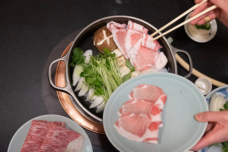 在Sukiyaki或Shabushabu的锅里放肉片和新鲜蔬图片