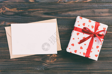 红心信封和黑暗木质背景的礼物盒图片