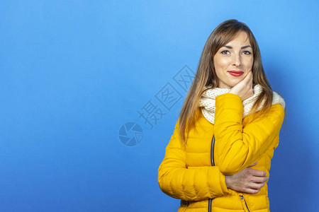 穿黄色夹克的年轻女子穿着蓝色背景的衣服概念是冬天和秋天图片