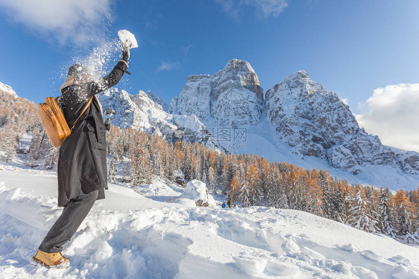 女人在意大利多洛米蒂山的佩尔莫山美丽的雪景前扔雪球图片