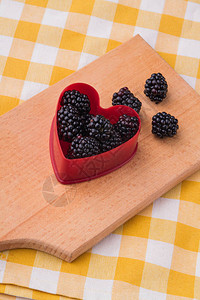 带有黑莓的红色塑料心形厨房木板顶视图图片