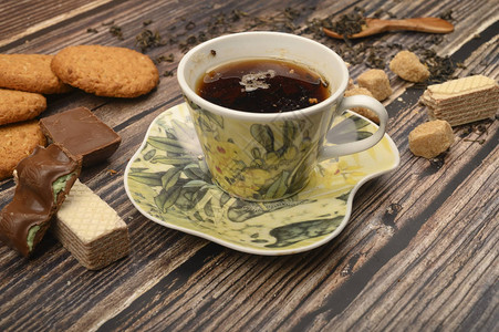 一杯黑茶叶棕色糖片燕麦饼干华夫饼木制背景的巧图片
