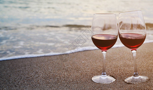 酒杯和红葡萄酒在沙滩上在沙图片