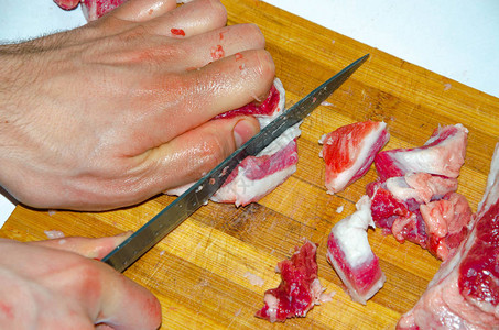 板上的生肉一个男人用刀把猪肉切成小块肉配培根生肉疾图片