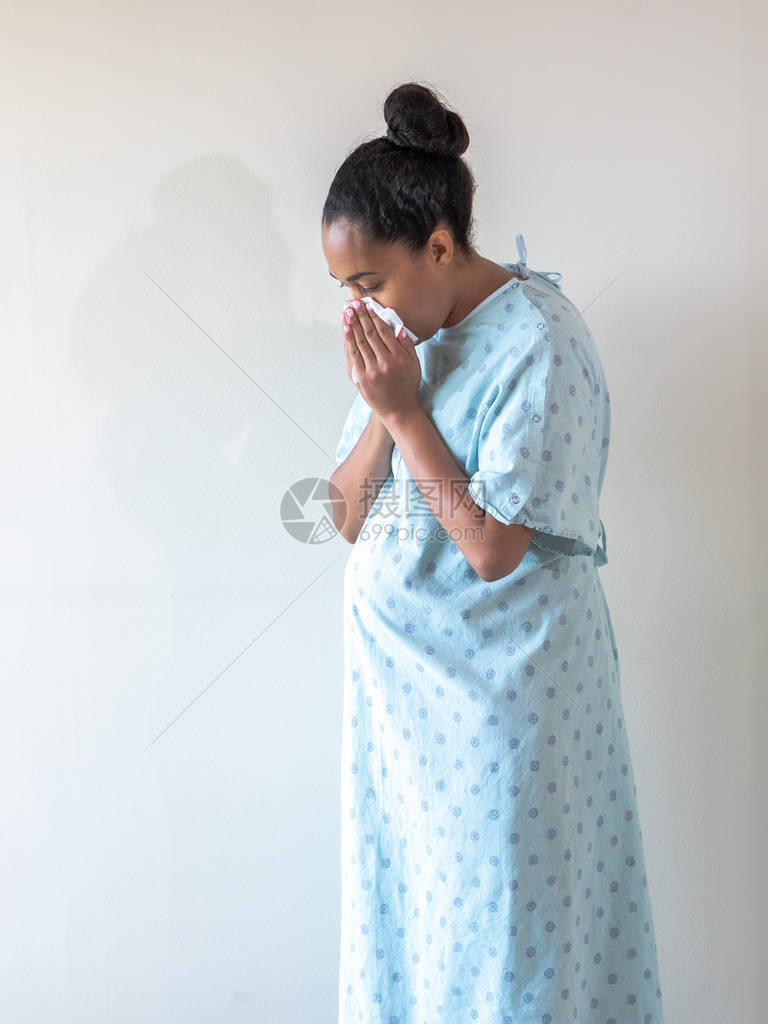 一名美籍非裔年轻混血女子穿着典型的医院礼服打喷嚏时图片