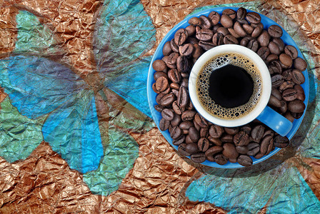 巴西咖啡蓝色杯咖啡与烤咖啡豆放在碟子上杯咖啡与蓝色大闪蝶的背图片