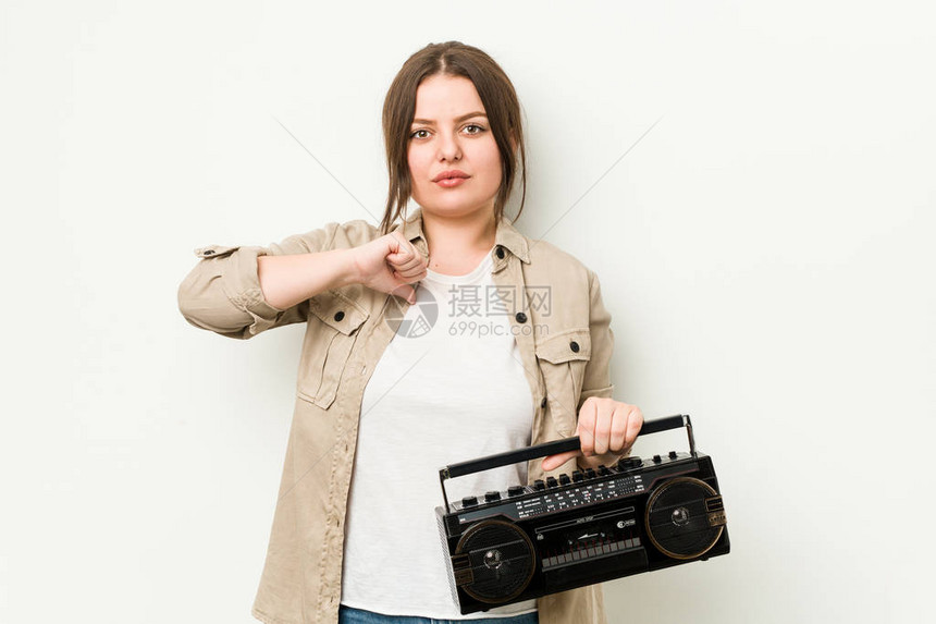 年轻的卷发女人拿着复古收音机表现出不喜欢的手图片