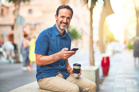 中年英俊的商人使用智能手机饮酒图片