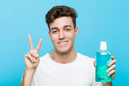 年轻的caucasian男子拿着一个口水洗涤显图片