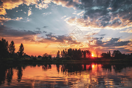 太阳落在湖面和森林的地平线上图片