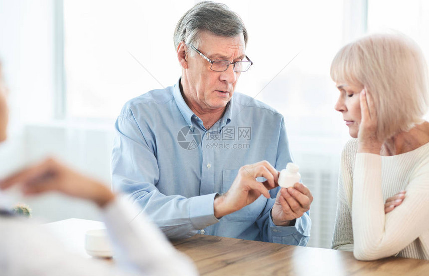 老年男子与妻子一起在医生办公室看药丸图片