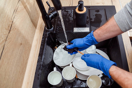 洗碗戴手套的男人用海绵洗碗图片