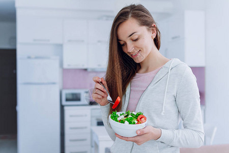 年轻快乐美丽的素食女人在家吃健康蔬菜沙拉作为午餐饮食和健身饮食清图片