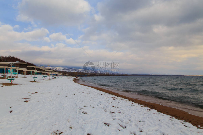 冬季海滩蓝色清澈的海水沙地上的雪地平线和山丘图片