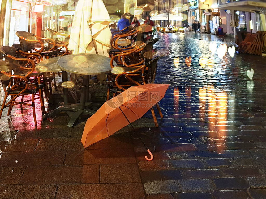 秋天将粉红和黑雨伞留在旧路面上图片