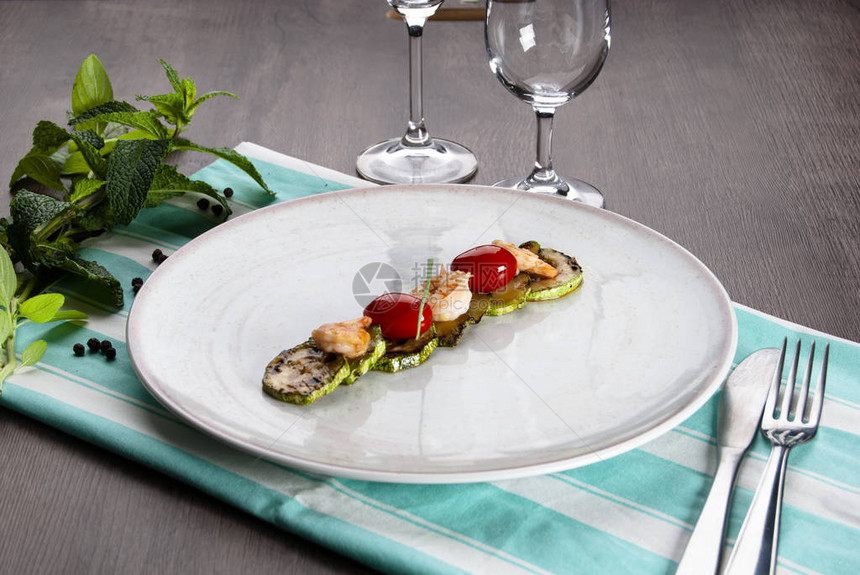 白色盘子上的樱桃西红柿和西红柿在带餐具和眼镜的条图片