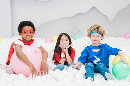 可爱的跨文化小伙伴在儿童房或幼儿园玩白色气球图片