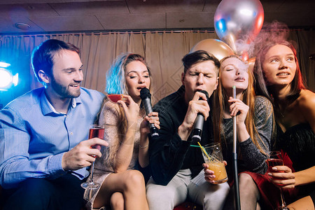 青年男女俱乐部员在卡拉OK酒吧度过时间背景图片