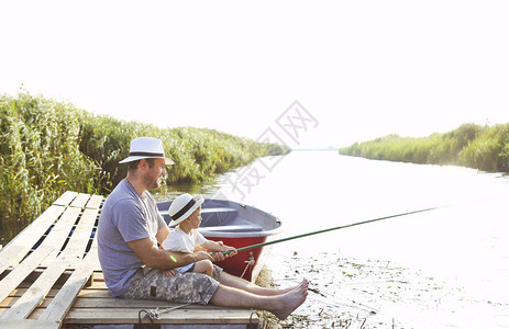 父亲和小儿子在河岸钓鱼图片