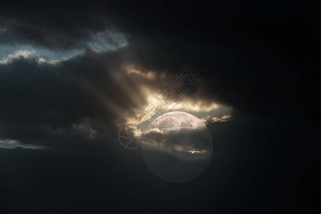 满月的亮在笼罩的夜晚光束从云中图片