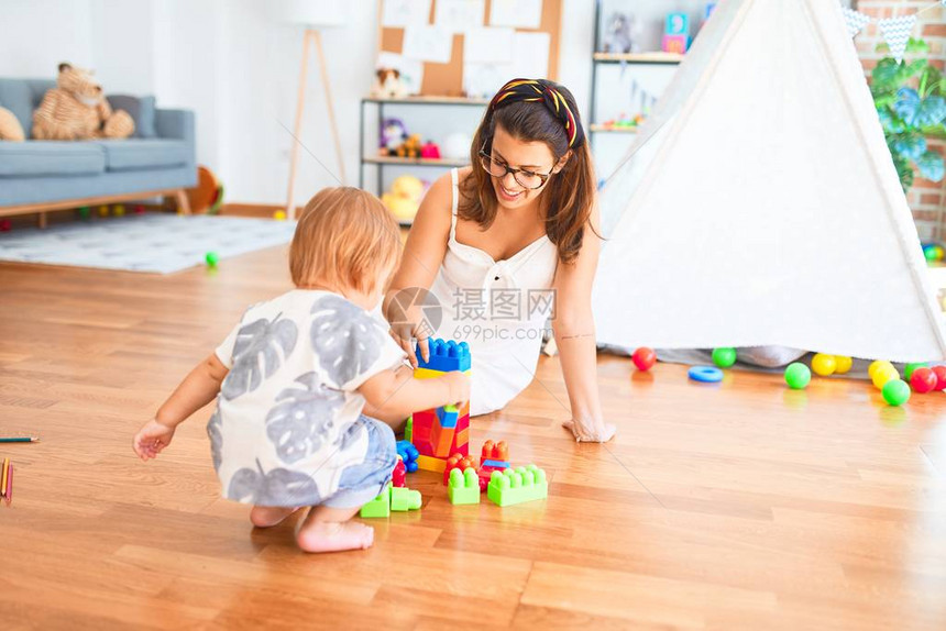 美的老师和幼稚园儿童在幼儿园玩许多玩具的图片