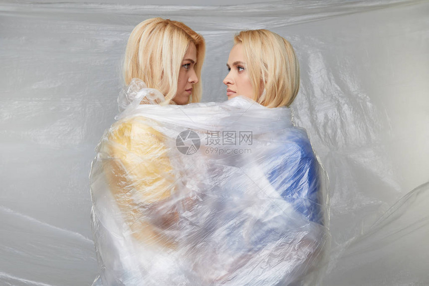 两名心烦意乱的年轻女被包裹在不可摧毁的聚乙烯中图片
