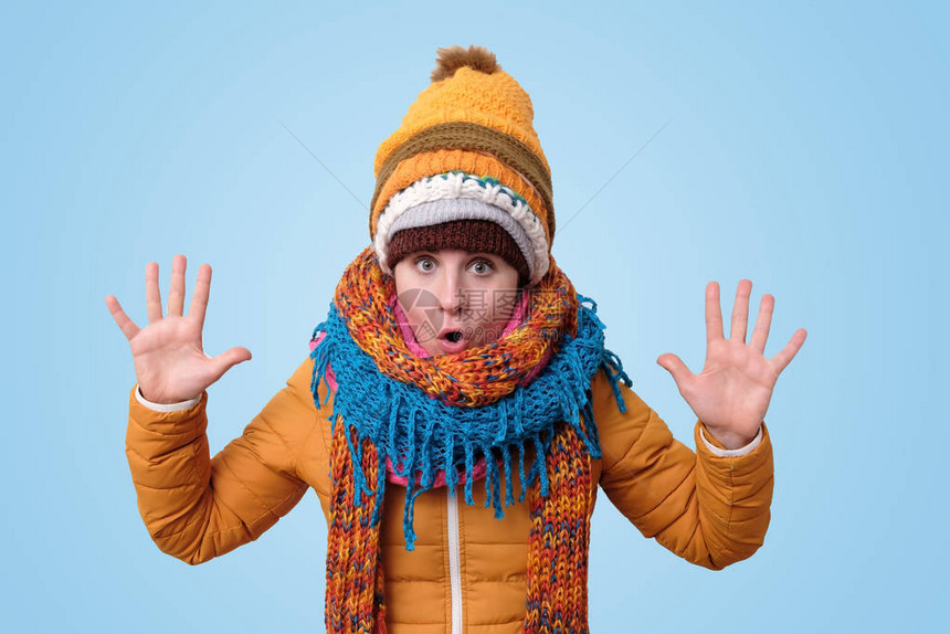 身着温暖衣服围巾和帽子的年轻caucasian女人展示了十根手指图片
