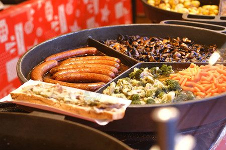 花椰菜蘑菇胡萝卜香肠在街头食品咖啡馆的大圆锅上煎图片