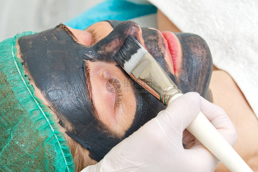 美容师将天然保湿面膜涂抹在年轻美女的脸上图片