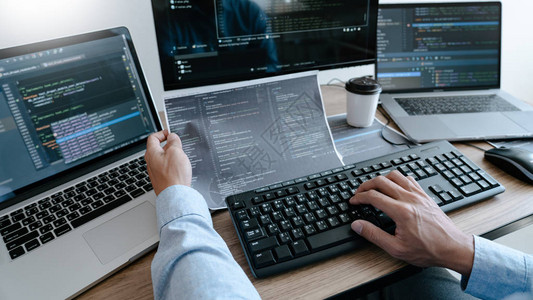 在IT办公室在计算机上工作的程序员在软件中键入数据编码并在计算机屏背景图片