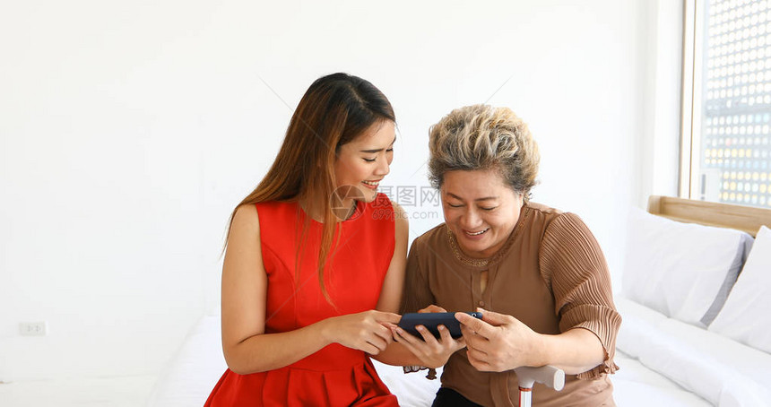 快乐的年轻女孩和一个年长妇女在家中与数字平板图片