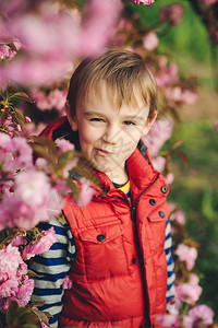 时尚男孩在春天自然背景下做鬼脸樱花树开花春天的花香图片